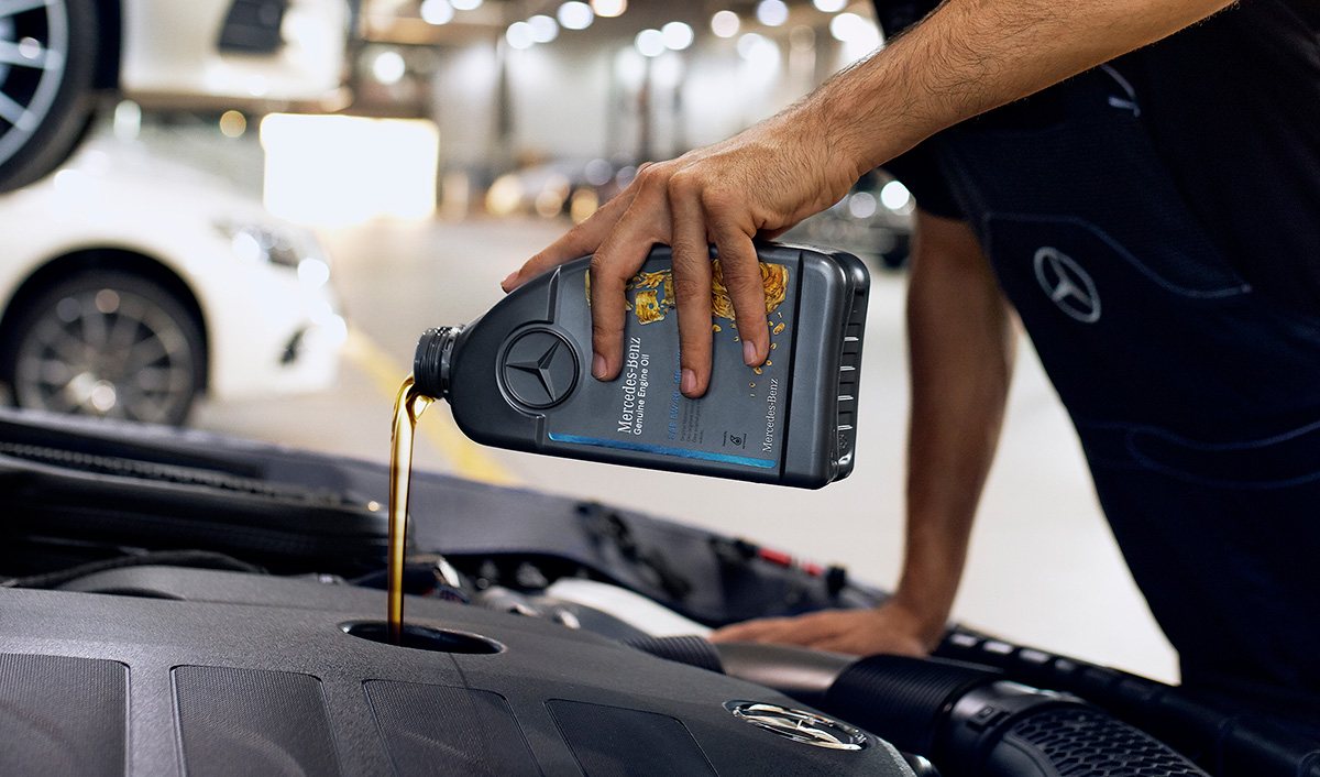 Werkstattmitarbeiter gießt Öl in den Motor